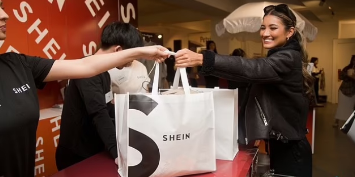 A young woman smiling while holding a Shein shopping bag, excited about her recent clothing haul.